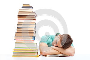 Sleeping student sitting at the desk with high books stack