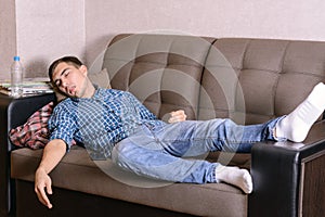 The sleeping young man on the couch in the room, tired after work, drunk after a party. Fell asleep anyhow.