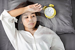 Sleepless Asian woman insomnia,overthinking lying down in bed with alarm clock show the time late at night photo