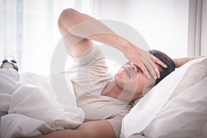 Sleepless hangover man on bed up with headache photo