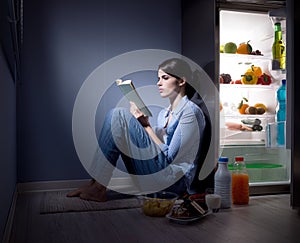 Sleepless woman reading in the kitchen