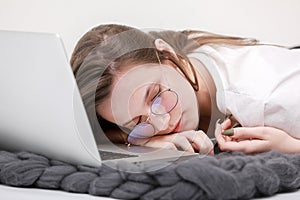 Sleeps in the workplace. Tired young woman working, headache, falling asleep on white background. Learns, using laptop computer on