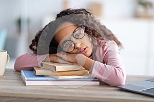Sleepy african-american teen girl resting head on paper books, tired of school, studying and reading
