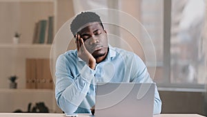 Sleepy african man young male employee investor businessman napping at office desk abruptly wake up shocked confused