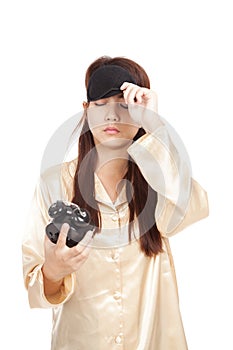 Sleepy Asian girl pull eye mask look at alarm clock
