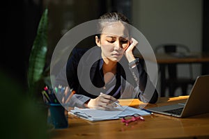 Sleepy and bored businesswoman sitting at her office desk