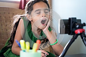 Sleepy boredom kid yawning during online class infront of mobilephone - concept of tired or bored child during