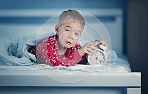 Sleepy boy lying in bed with blue beddings