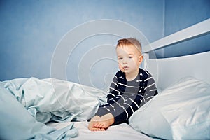 Sleepy boy sitting in bed