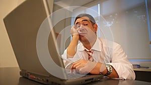 Sleepy businessman using laptop in office