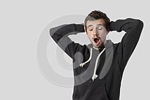 Sleepy caucasian young man calmly yawns. Isolated on white background