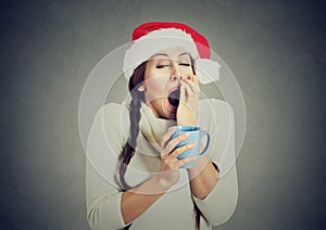 Sleepy christmas woman yawning holding cup of hot beverage