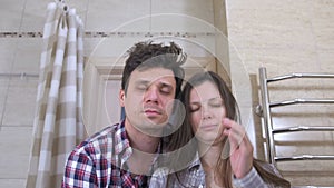 Sleepy couple man and woman in the bathroom with hangover trying to Wake up and smiling.