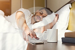 Sleepy guy waking up early after alarm clock signal