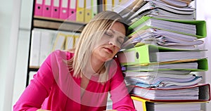 Sleepy lady office worker sits by enormous stack of documents