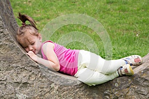 Sleepy Little Girl Resting On The Stonewall In The Park