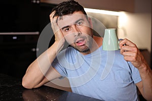 Sleepy looking man holding coffee cup upside down