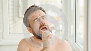 Sleepy man cleans teeth electric toothbrush