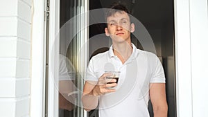 Sleepy man drinks cup of coffee for awakening on balcony