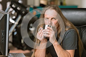 Sleepy Man at his Desk with Coffee and Motorcycle in the Background