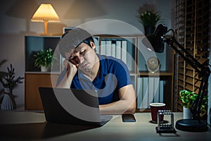 sleepy man working with laptop at night