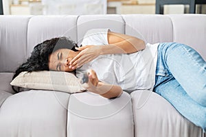 Sleepy mixed-race girl holding tv remote controller