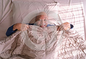 Sleepy old elderly black man yawning. African American people lying and sleeping on bed in bedroom in early morning at home.
