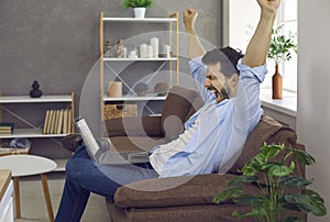 Sleepy tired young man stretching arms and yawning while working on laptop at home