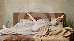 Sleepy unrecognizable woman waking up lying in comfortable white bed unknown girl stretching female hands with soft skin