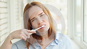Sleepy woman cleans teeth electric toothbrush
