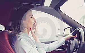 Sleepy woman driving her car after long hour trip isolated street background.