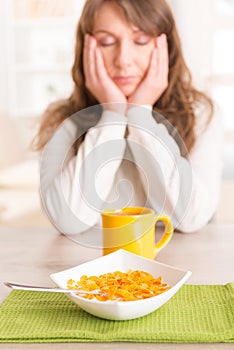 Sleepy woman eating breakfast at home