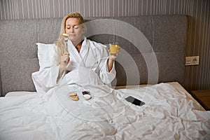 Sleepy woman having breakfast in her hotel room in morning
