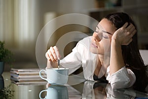 Sleepy woman stirring coffee in the morning