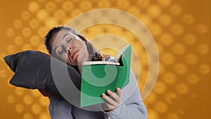Sleepy woman struggling to keep eyes open while reading book, studio background