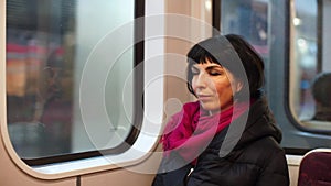 A sleepy woman in a subway train arrives at the station.