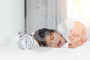 Sleepy woman trying turn off alarm clock in the morning