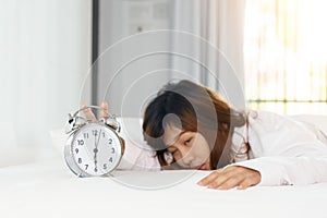 Sleepy woman trying turn off alarm clock in the morning