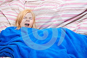 Sleepy woman yawn in a duvet