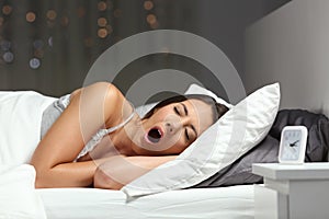 Sleepy woman yawning ready to sleep on a bed