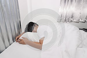 Sleepy young Asian man with blindfold eye mask comfortably sleeping on the white bed in bedroom