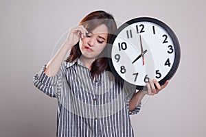 Sleepy young Asian woman with a clock in the morning.