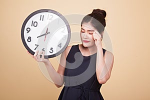 Sleepy young Asian woman with a clock in the morning.