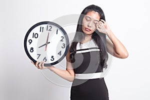 Sleepy young Asian woman with a clock in the morning