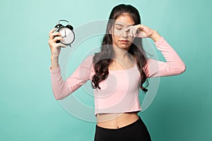 Sleepy young Asian woman with a clock in the morning