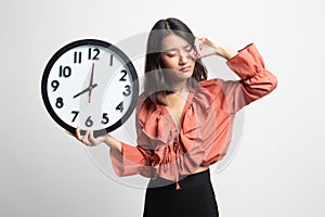 Sleepy young Asian woman with a clock in the morning