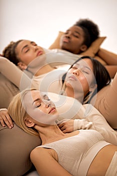 sleepy young diverse ladies lying on floor in studio, calm and pacified, isolated