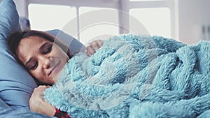 Sleepy young pretty woman lying in bed waking up stretching and smiling ob blurred window on the background. slow motion