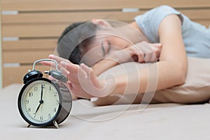 Sleepy young woman in bed with eyes closed extending