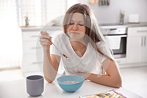 Sleepy young woman eating breakfast at home in morning